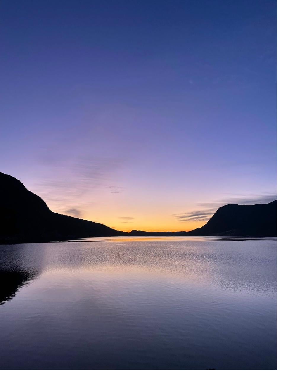 Mirror-still fjord at sunset with mountains